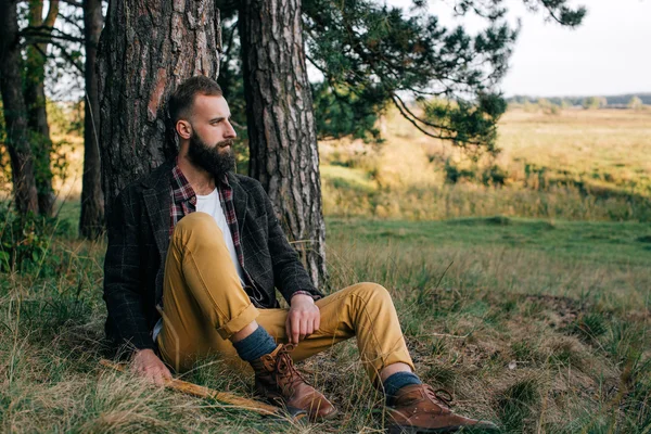 Retrato brutal barbudo hipster homem na floresta com machado — Fotografia de Stock