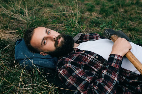Портрет жорстокого бородатого хіпстера в лісі з сокирою — стокове фото
