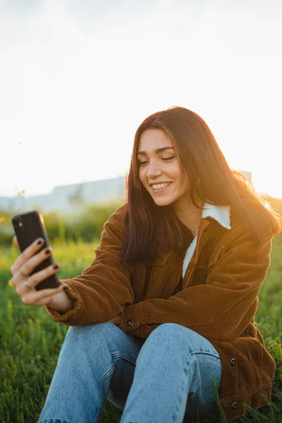 Teenager Video Volá Přítele Zatímco Sedí Zelené Louce Během Západu — Stock fotografie