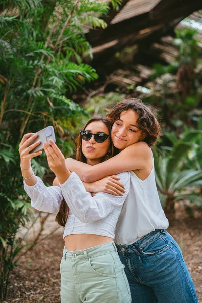 Две Девочки Подростки Делают Селфи Парке Пока Обнимаются Веселятся Кажутся — стоковое фото