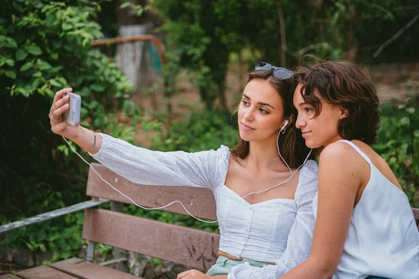 Dvě Dospívající Dívky Selfie Zatímco Sedí Lavičce Parku — Stock fotografie