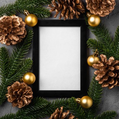 Boş çerçeveli Noel kompozisyonu. Altın süs, çam kozalakları ve köknar iğneleri. Tebrik kartı şablonunu düzenle
