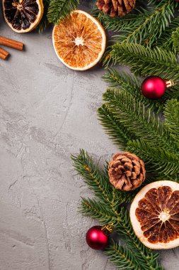 Noel kompozisyonu. Toplar, tarçın, anason, kurutulmuş meyveler, kozalaklar ve gri arka planda köknar iğneleri. Üst görünüm kopyalama alanı
