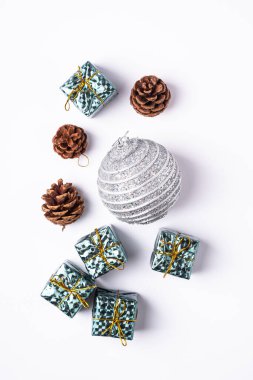 Yeni yıl kompozisyonu. Hediyeler, köknar ağacı konileri, beyaz arka planda gümüş top süslemeleri. Kış tatili konsepti. Düz yatış, üst görünüm