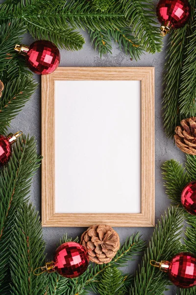 Christmas holidays composition with picture frame mockup. Red baubles and fir-tree branches.