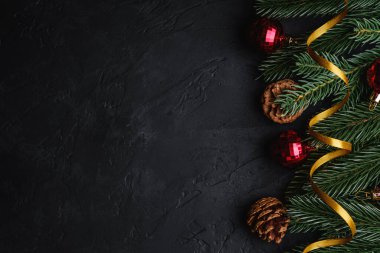 Noel tatili kompozisyonu. Altın kurdele, kırmızı süs ve mücevherler, köknar ağacı ve çam kozalakları. Boşluğu kopyala