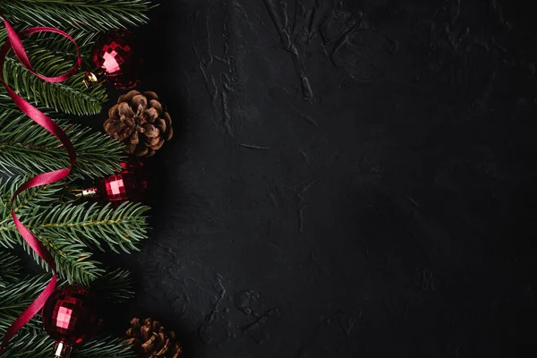 Noel tatili kompozisyonu. Kırmızı kurdele, süs ve takı süsleri, köknar ağacı ve çam kozalakları. Boşluğu kopyala