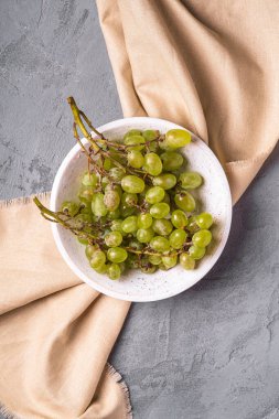 Taze beyaz üzüm üzümleri ahşap kasede keten masa örtüsü, taş beton arka plan, üst manzara.