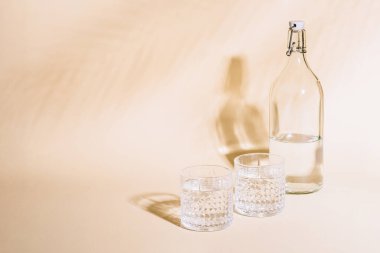 Pastel arka planda, şişenin yanında bir bardak su.