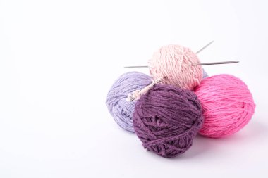 Renkli iplik topları ve beyaz arka planda örgü iğneleri