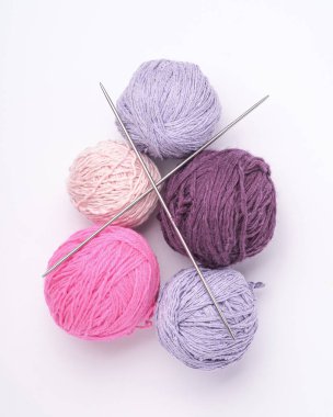 Renkli iplik topları ve beyaz arka planda örgü iğneleri