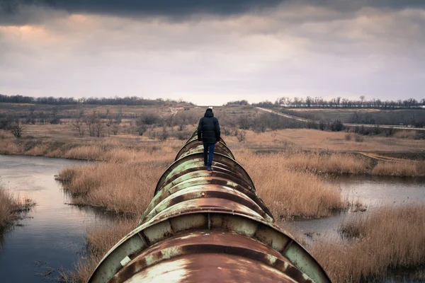 Man walking on old rusty transportation pipeline. Environment and fuel energy concept.