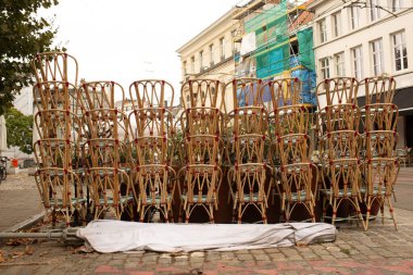 Bir parke taşı sokağındaki bir restoranın önünde sıralanmış rattan kafe sandalyeler. Şehir yaşamını, açık hava yemeklerini ya da restoran kapanmasını sembolize eden şehir manzarası.