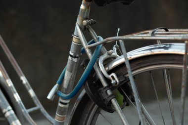 Arka tekerinde mavi kilit olan klasik bir şehir bisikletinin yakın çekimi. Kentsel yaşam tarzı ve ulaşım kavramı.