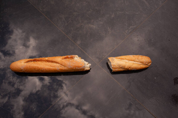 Багет с видимой плесенью на темных плитках с небом. Концептуальный редакционный кадр, символизирующий финансовый и моральный упадок.