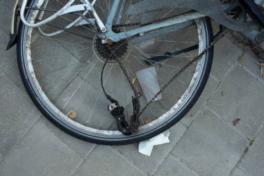 Asfaltlı bir şehir yüzeyindeki bisiklet tekerleği ve zincirinin detaylı bir yakın çekimi. Bisiklet dostu bir şehirden tipik bir nakliye sahnesi.