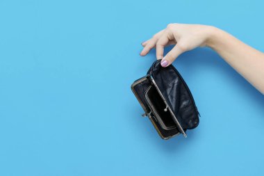 Fotokopi alanı olan mavi arka planda boş bir cüzdanı tutan bir kadın. Parasızlık. Yoksulluk ve iflas kavramı