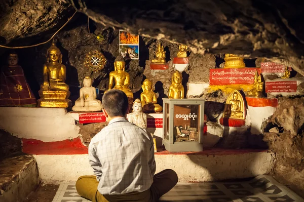 A faithful praying in front of statues of the Buddha — Stock Photo, Image