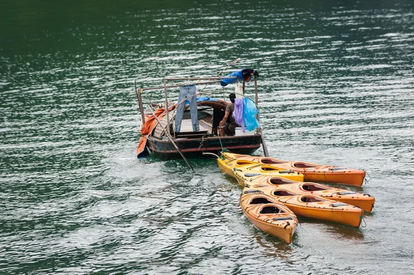 Small boat towing colorful kayaks — Stock Photo, Image