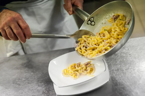 Cocine prepara gramigna con salchicha de cerdo en un plato —  Fotos de Stock