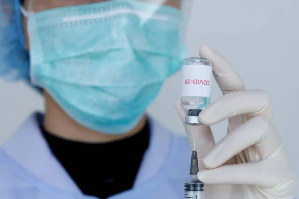 Doktor, Coronavirus tedavisi için şırınga ve aşıyla dolu bir şişe tutuyor. İlaç tedavisi kavramı.