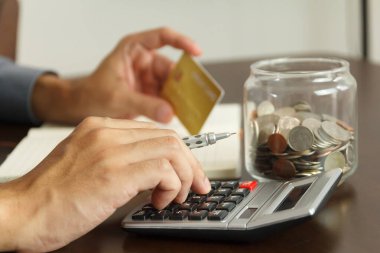 Para yönetimi konsepti. El adamı, kredi kartı borcunu ödemek için bütçeleri hesaplamak için hesap makinesi kullanıyor..