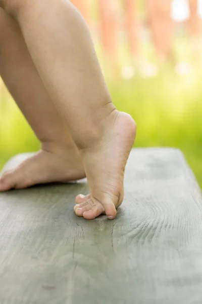 Legs of a small child, standing on a bench — Stock Photo, Image