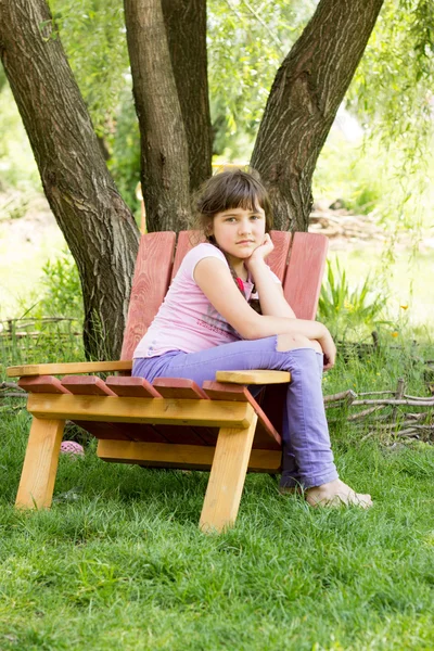 Een klein meisje van 8 jaar, brunette in paarse spijkerbroek, een roze T-shi — Stockfoto