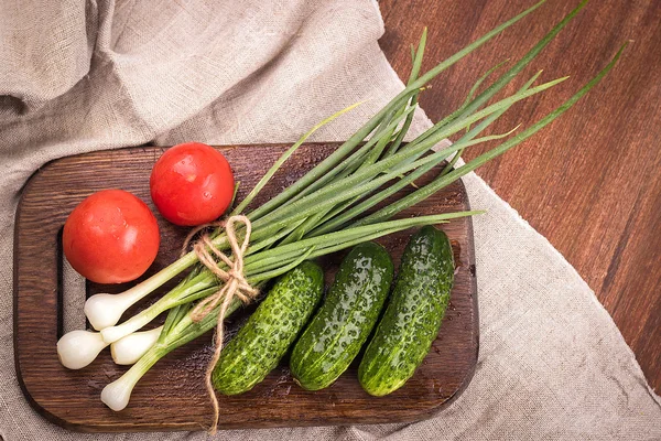 Ung grön lök, ung grön gurka, tomat, sallad på en wo — Stockfoto