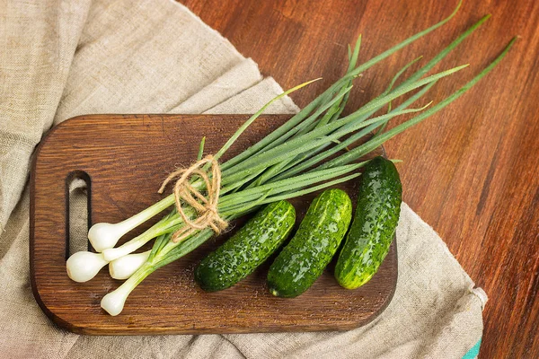 Ung grön lök, ung grön gurka på en trä hugga boa — Stockfoto