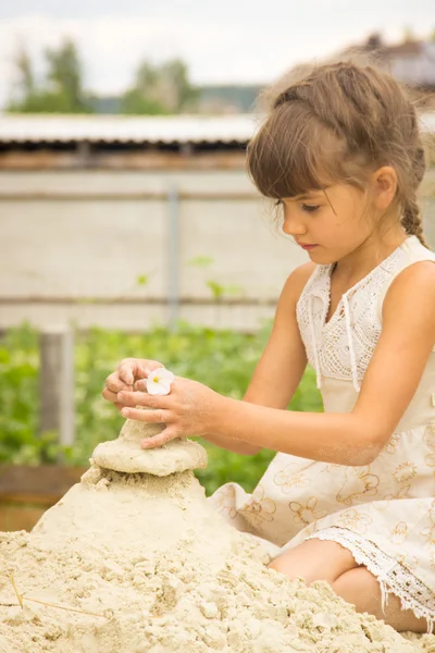 Kleines Mädchen, brünettes Haar zu einem hellen Kleid geflochten spielt in der — Stockfoto