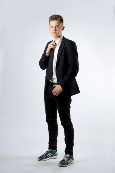 A young boy, brunette student in a black suit on a white backgro — Stock Photo, Image