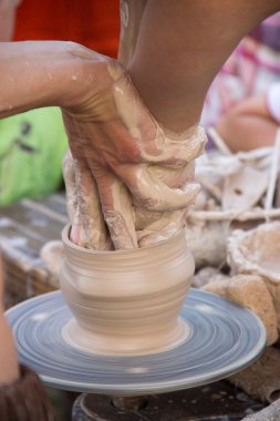 hands in the clay, four hands molded clay, the clay on a potter'