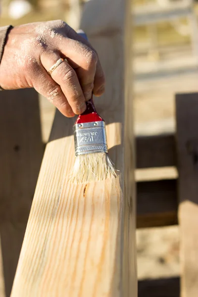 Cahaya balok kayu, tangan orang itu memegang kuas dan cat wo — Stok Foto