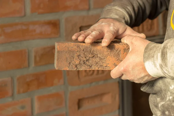 Men's hands are kept carved brick on brick wall background, man' — Stock fotografie