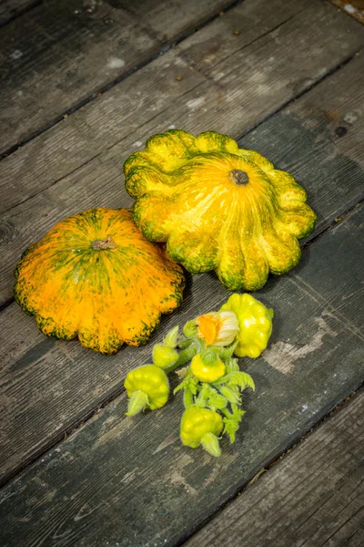 Patisson pequeno amarelo, abóbora laranja em uma aba velha redonda de madeira — Fotografia de Stock