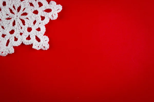 snowflakes crocheted from white thread on a red background
