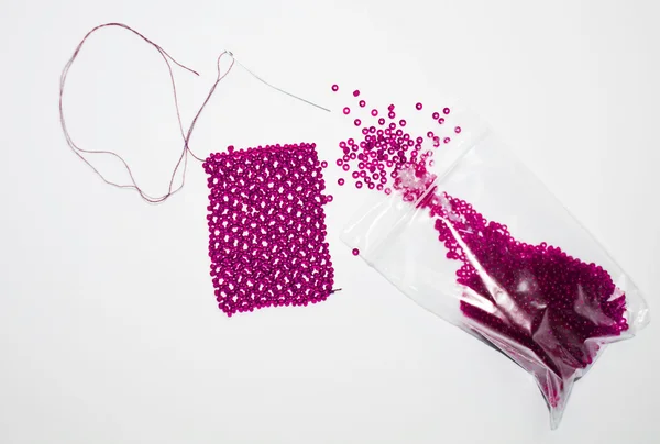 Pink beads in a package and needle — Stock Photo, Image