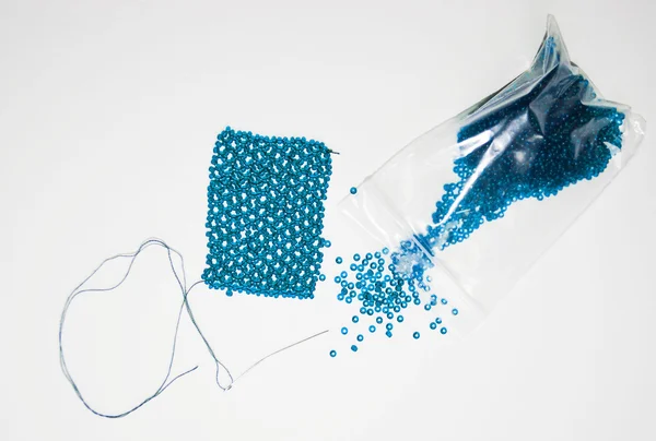 Blue beads in a package and needle — Stock Photo, Image