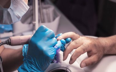 Çivi ustası insan için manikür yapıyor. Yakın plan mavi eldivenler ve erkek eli.