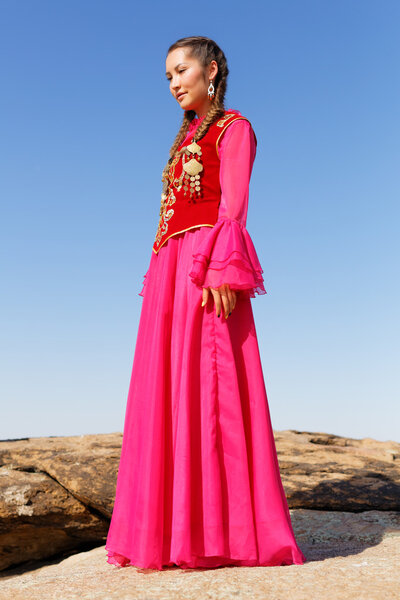 Beautiful kazakh woman in national costume in the steppe dancing with dombyra