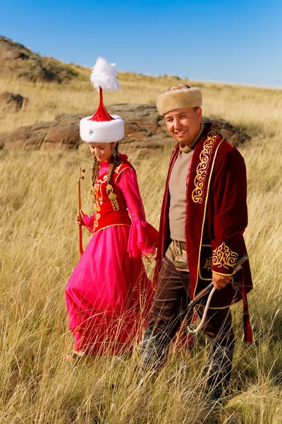 Kazajstán hombre y mujer en trajes nacionales en la estepa jugando dombyra y bailando — Foto de Stock