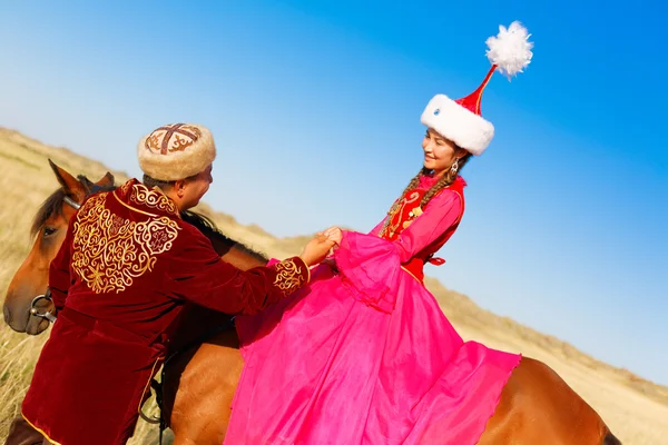Kasachische Männer und Frauen in Nationaltrachten in der Steppe spielen Dombyra und tanzen — Stockfoto