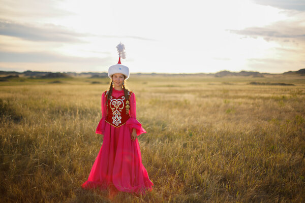 Beautiful kazakh woman in national costume in the steppe dancing with dombyra