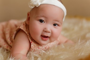 Beautiful cute baby girl with bow on the fur ground clipart