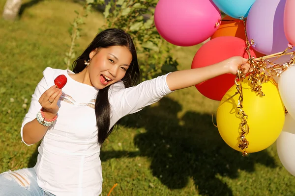 Güzel Kazak kız balonlar ve parkta çilek ile