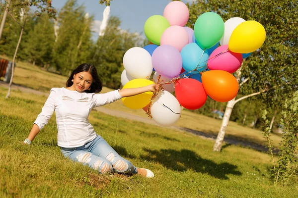 Mooi kazakh meisje met ballonnen en aardbei in het park — Stockfoto