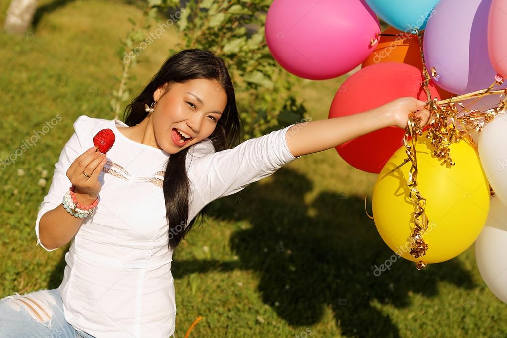 Beautiful kazakh girl with balloons and strawberry in the park