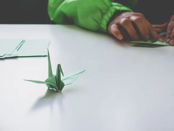 Papper Crane Origami fågel med hand vika på bord — Stockfoto
