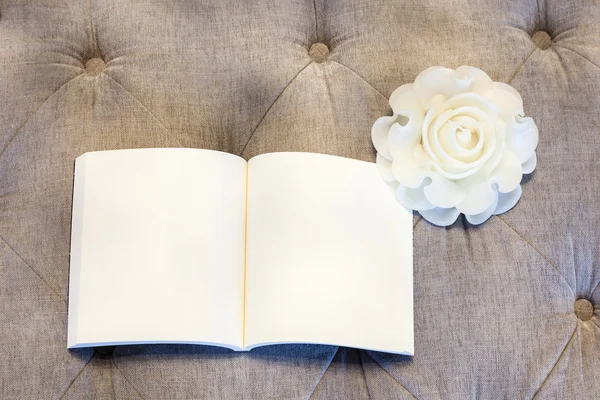 Libro en blanco con vela rosa en el sofá — Foto de Stock